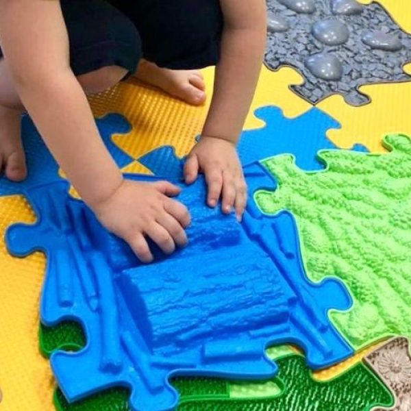 Child playing with a sensory playmat Blue tile