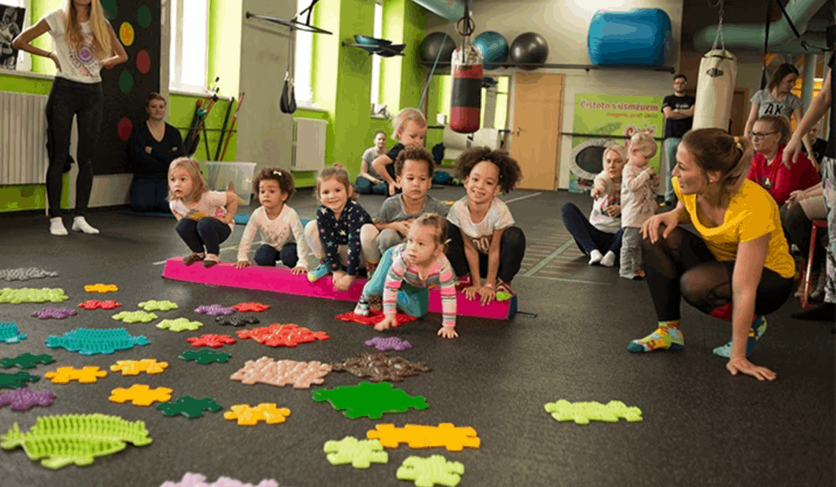 Happy children play with muffik sensory play mats with teachers during a session in a nursery